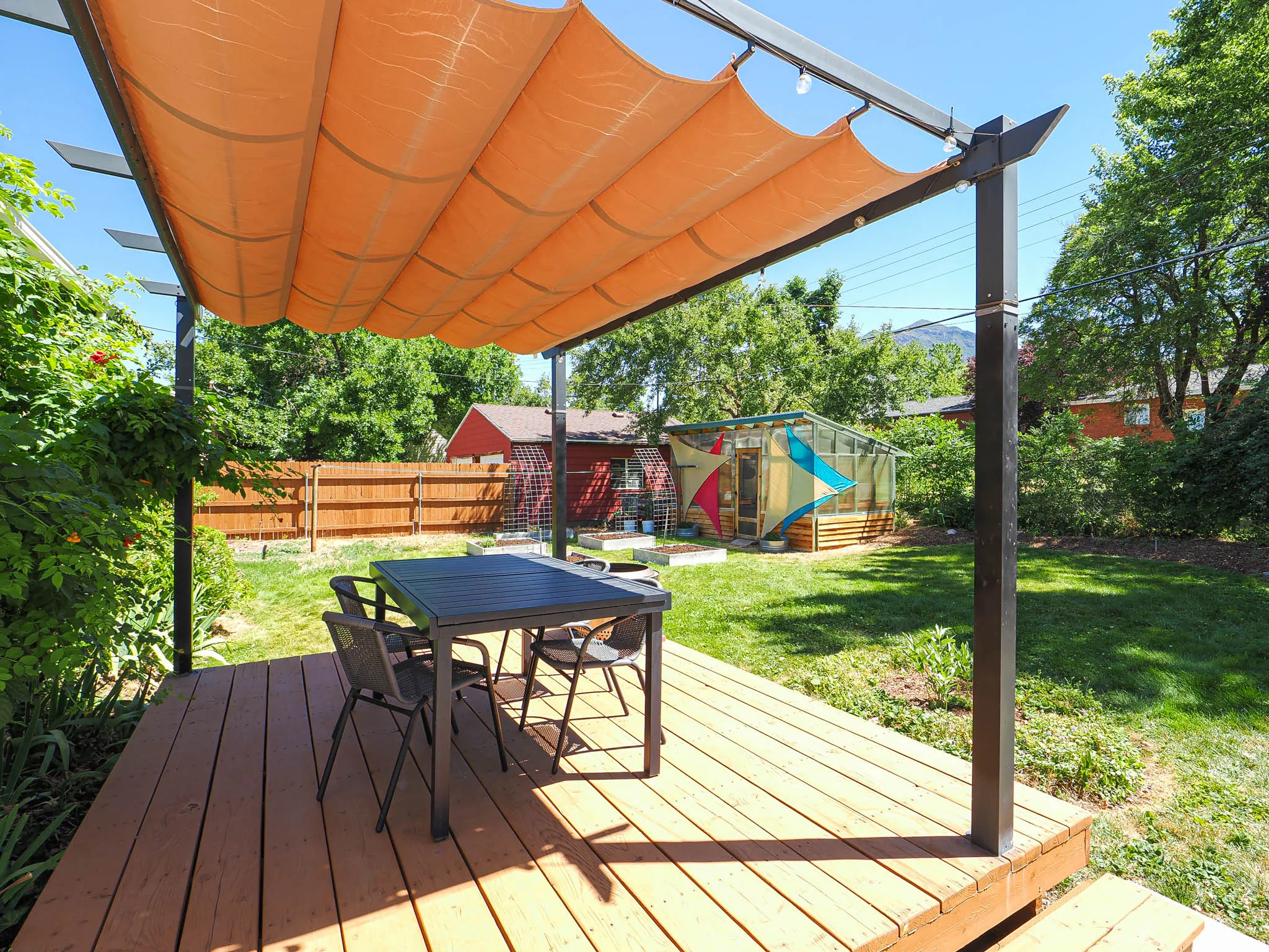 Expansive backyard featuring a wood-finish deck with a retractable fabric pergola
