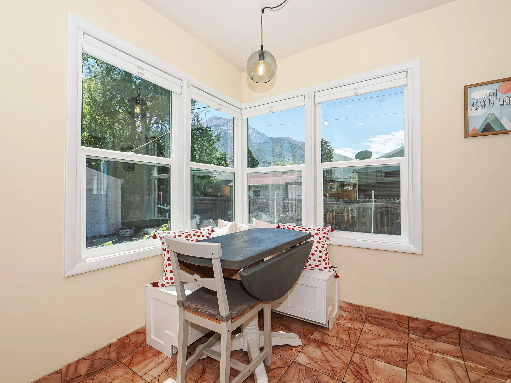 Corner window seating area featuring white window frames and a contemporary pendant light fixture