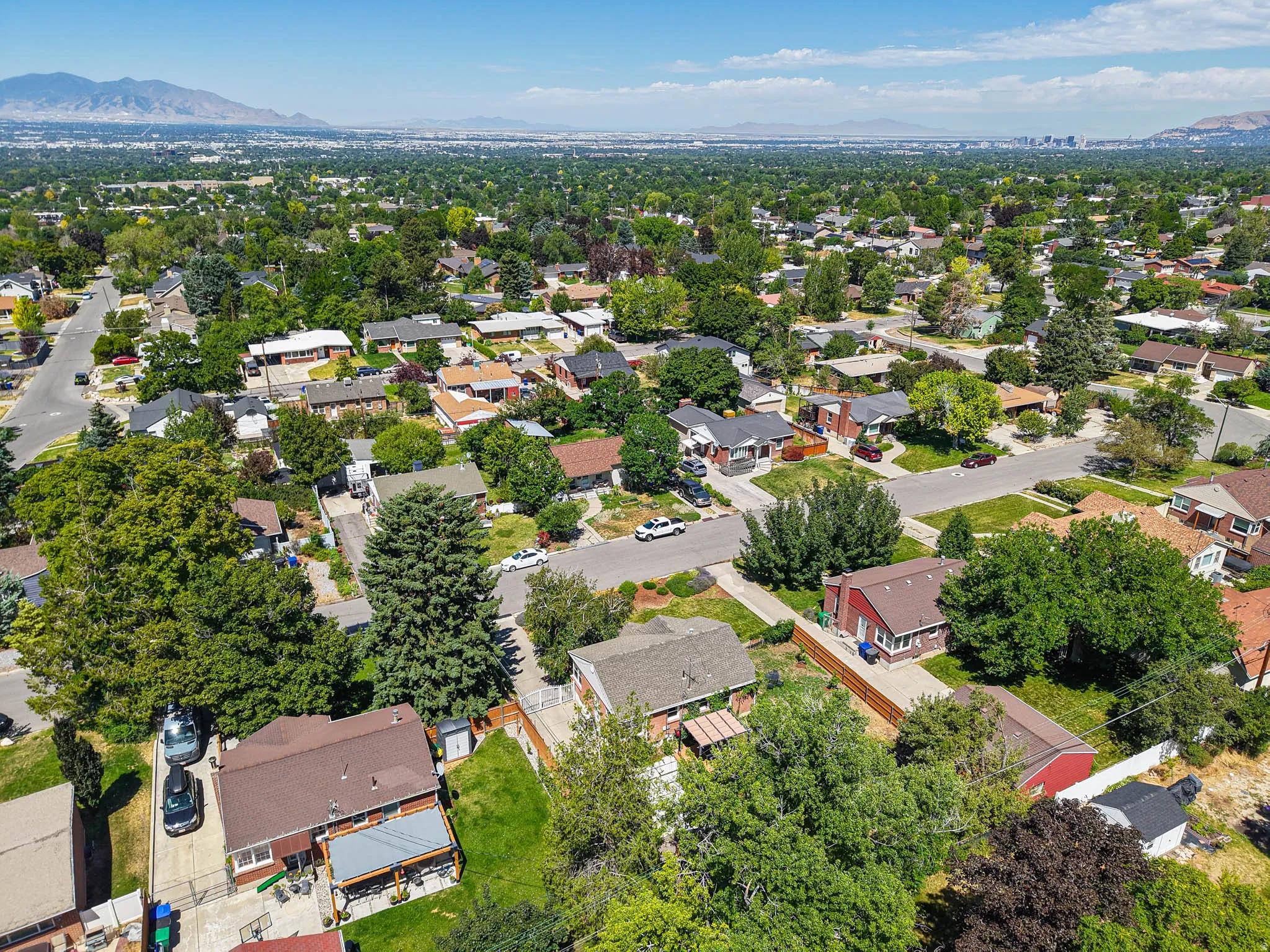 Residential area featuring mature trees, paved streets, and a mountainous backdrop