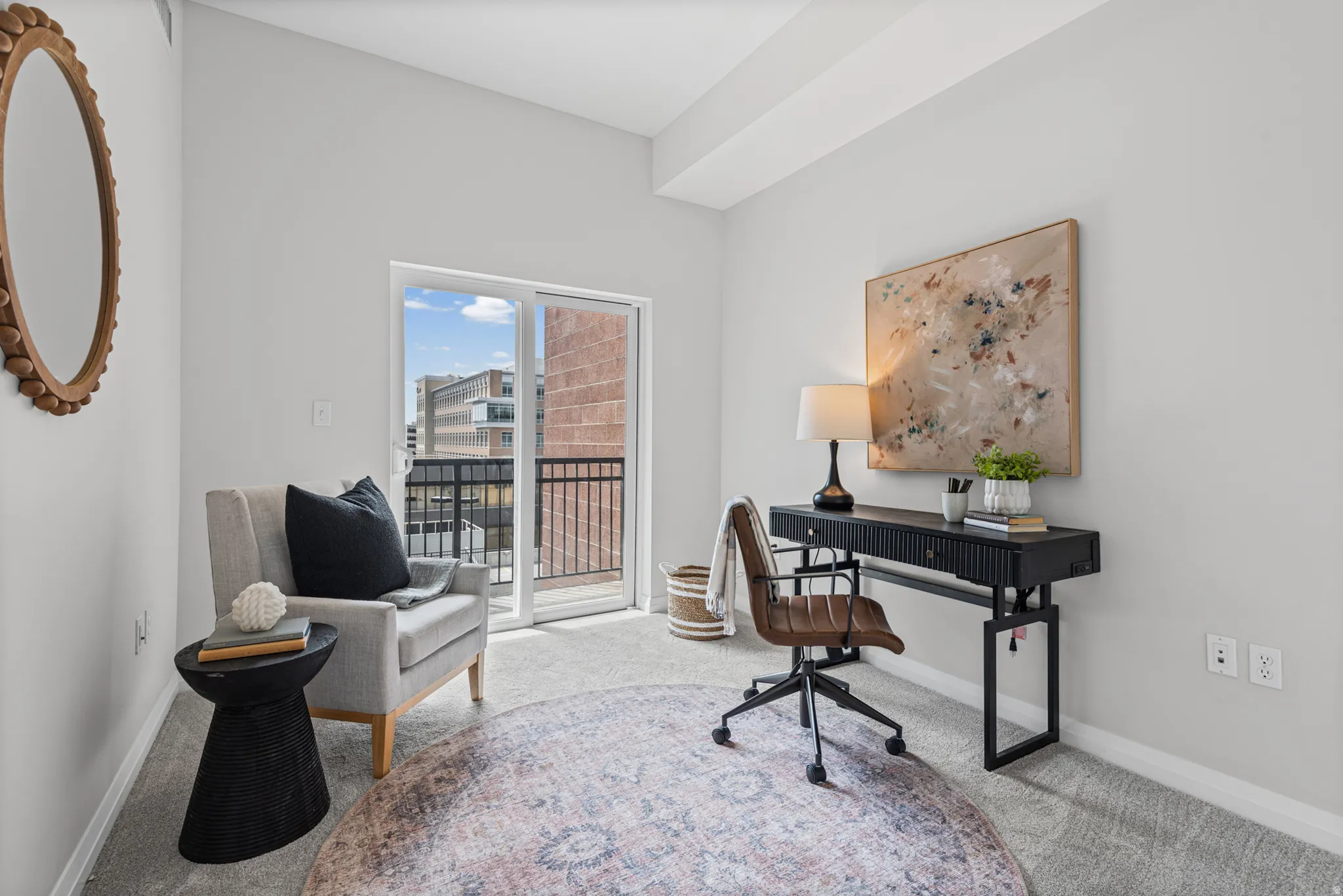 Light-filled room featuring a sliding glass door opening to a private balcony, neutral carpeting, and contemporary wall finishes