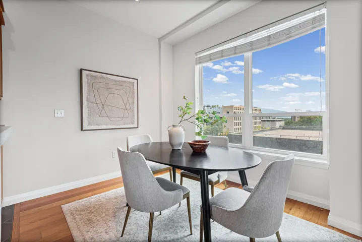 Bright dining area with expansive window, wood-finish flooring, and light-toned wall finishes