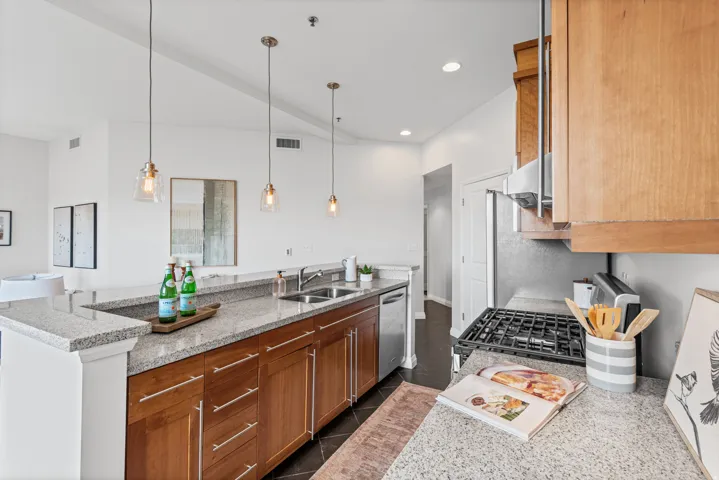 Kitchen featuring granite countertops, wood-finish cabinetry, stainless steel appliances, and a gas range