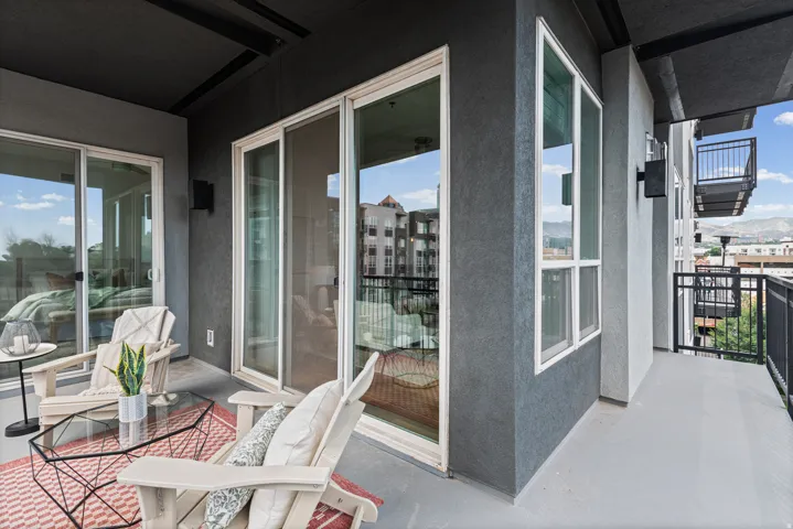 Private balcony featuring a concrete floor, dark gray exterior walls, and multiple sliding glass doors