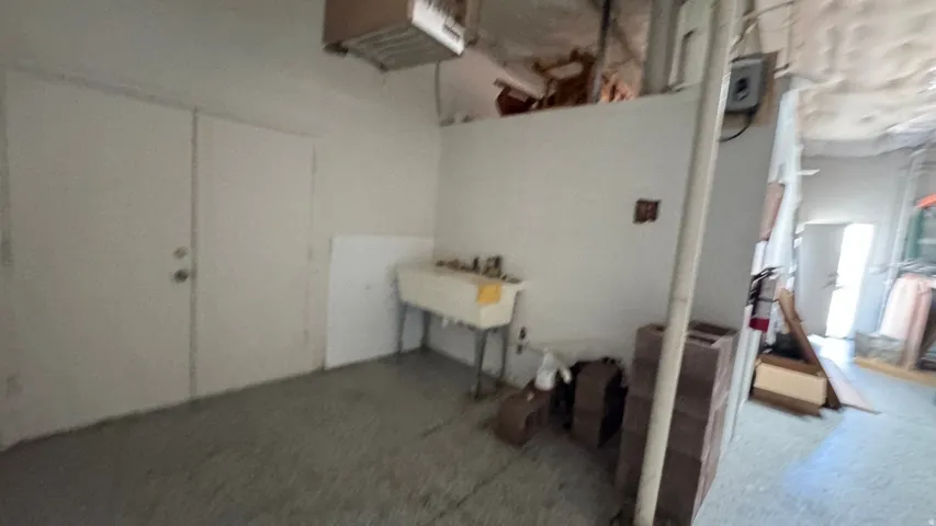 Utility area featuring a built-in wash basin, concrete flooring, and double utility doors