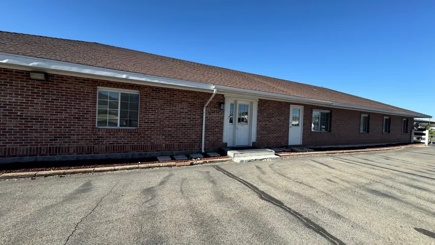 Brick exterior with multiple windows and two white entry doors