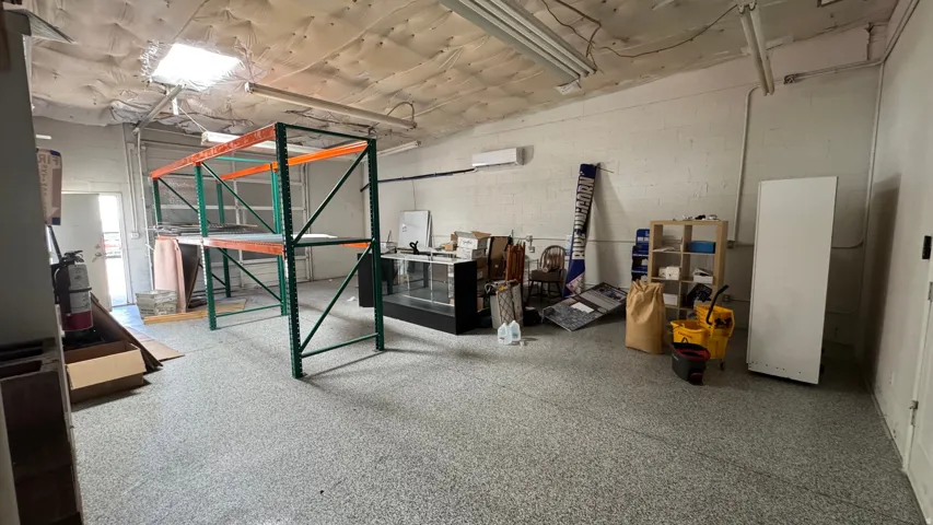 Spacious commercial interior featuring a roll-up garage door, skylight, and durable epoxy flooring