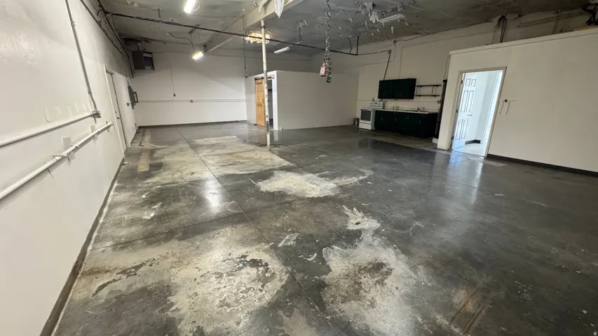 Spacious open-concept commercial interior featuring concrete flooring and white painted walls