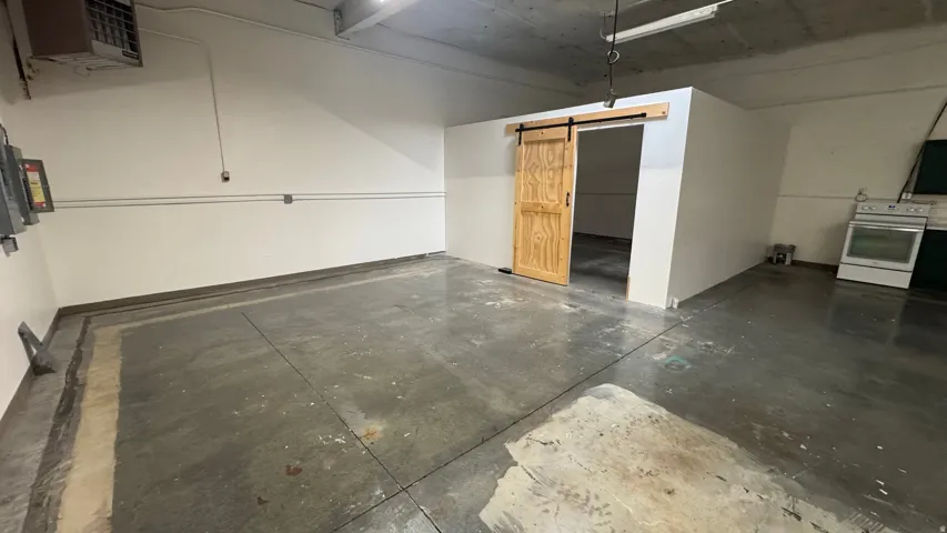 Spacious concrete floor area with white walls and exposed ceiling