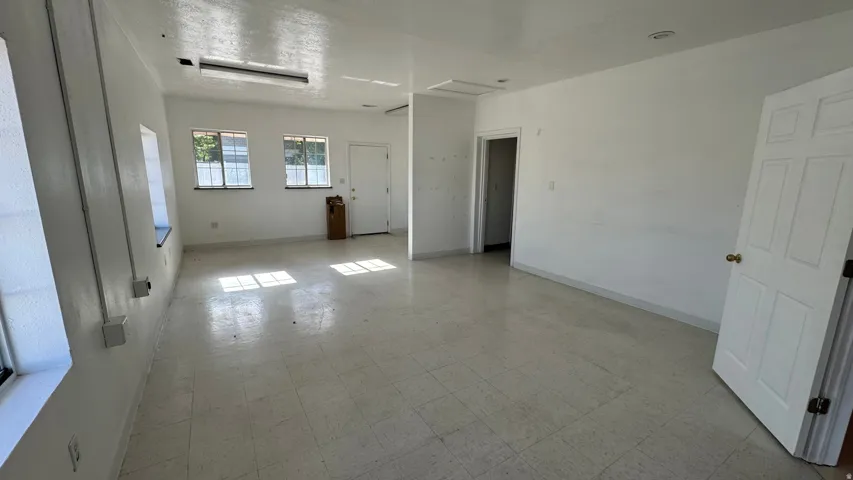 Spacious interior room with light-toned tiled flooring and white painted walls