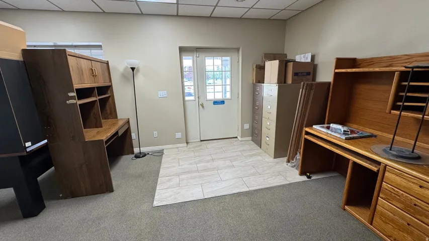 Commercial space featuring mixed flooring of light-toned tile and carpeting