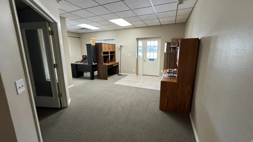 Carpeted office space with neutral wall tones and a drop ceiling