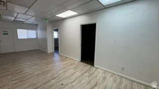 Spacious room featuring wood-finish flooring, white walls, and a drop ceiling with recessed lighting