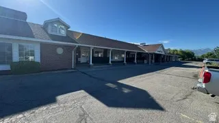Commercial strip center featuring a red brick facade, white siding, and a prominent dormer window