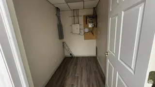 Compact utility room featuring wood-finish flooring, drop ceiling, and light-toned walls