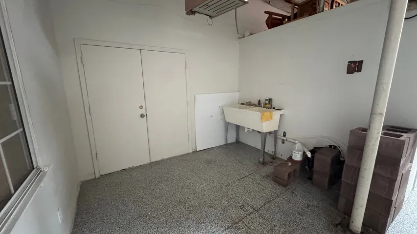 Utility area featuring a double-door entry, a functional utility sink, and a window with security bars