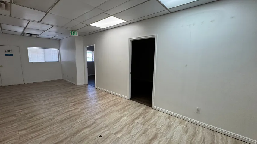 Spacious interior featuring neutral tone tile flooring, white walls, and a dropped ceiling with integrated lighting