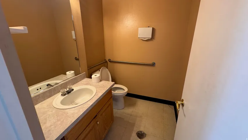 Functional bathroom featuring a wood-finish vanity with integrated sink, laminate countertop, and chrome faucet