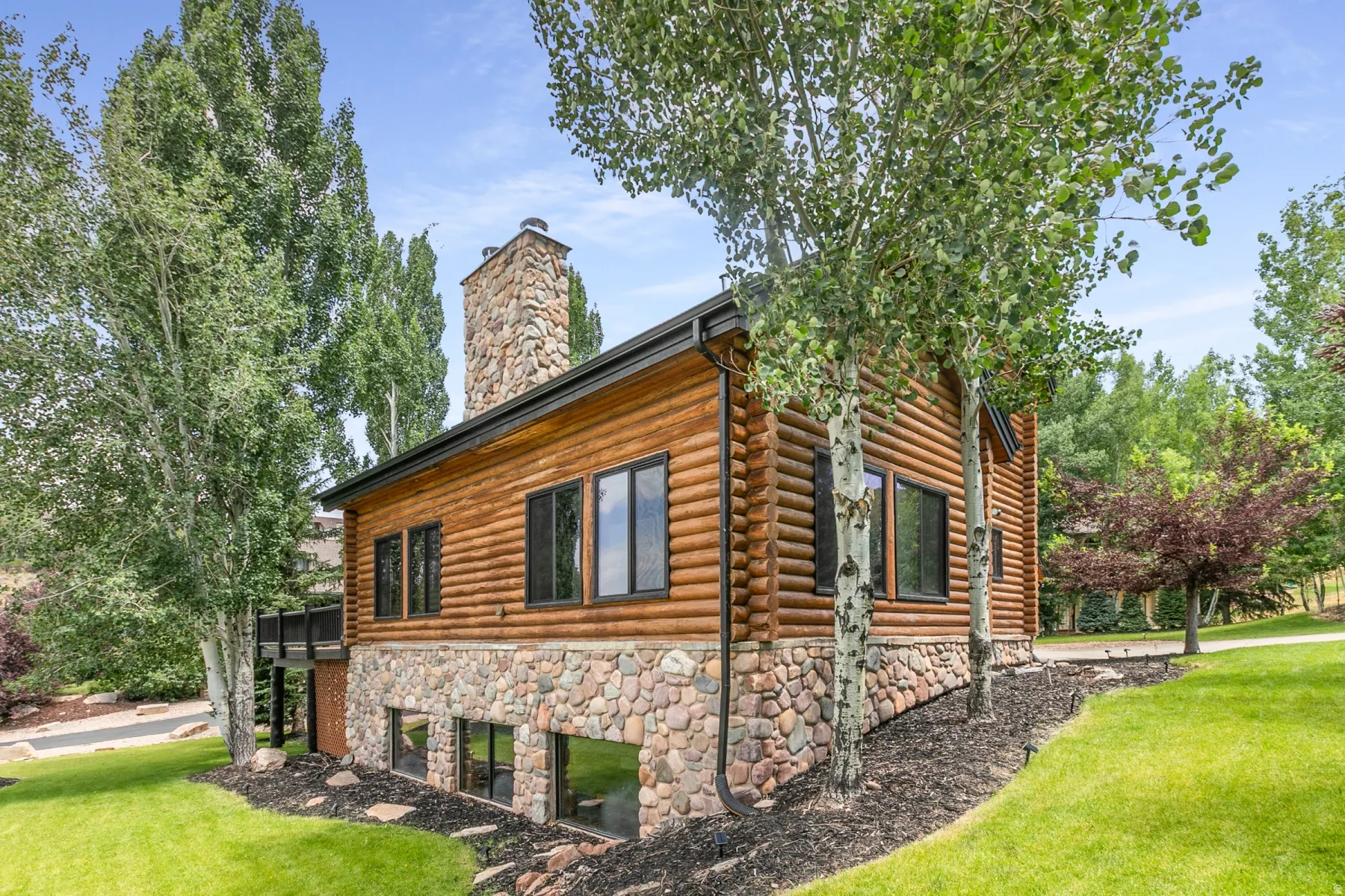 Log-sided residence featuring a stone foundation and chimney
