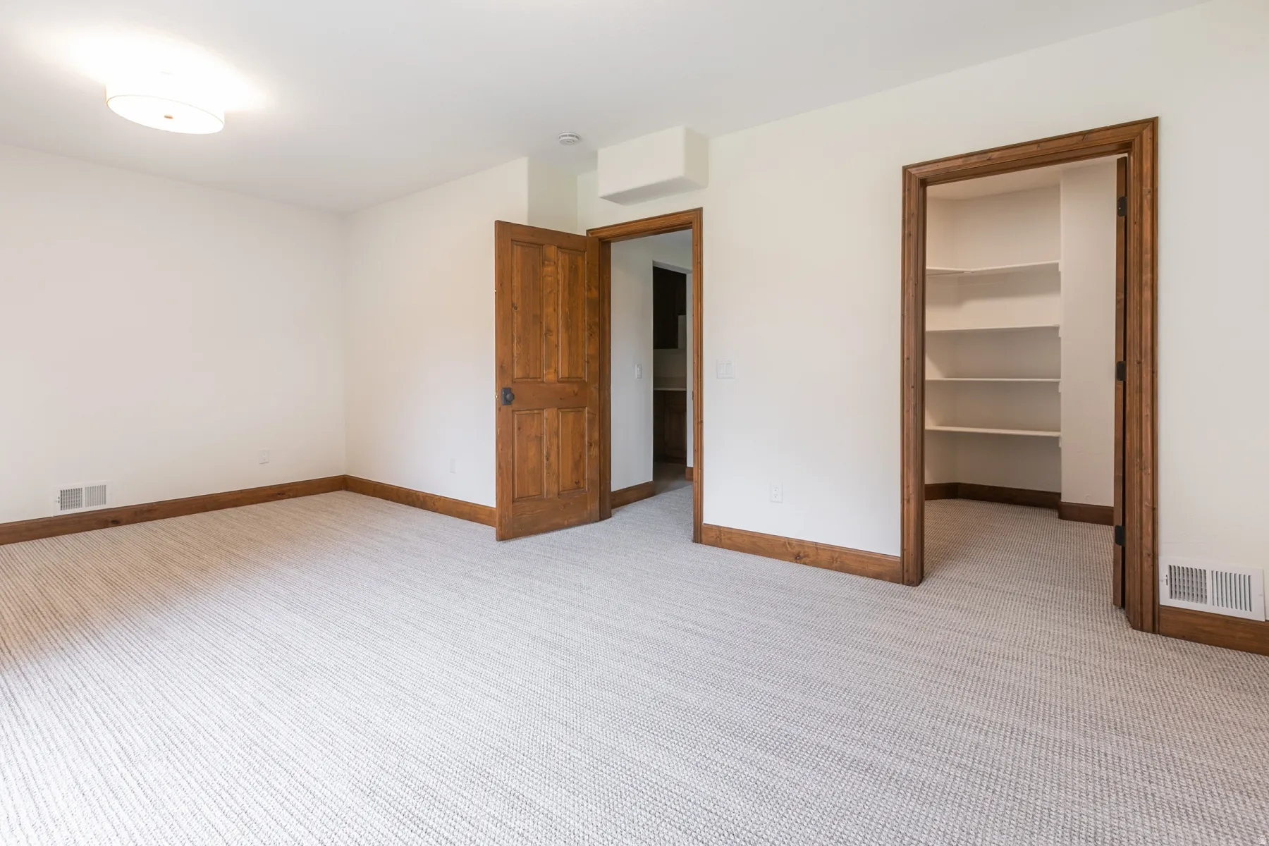 Neutral-toned carpeted room featuring white walls and natural wood trim