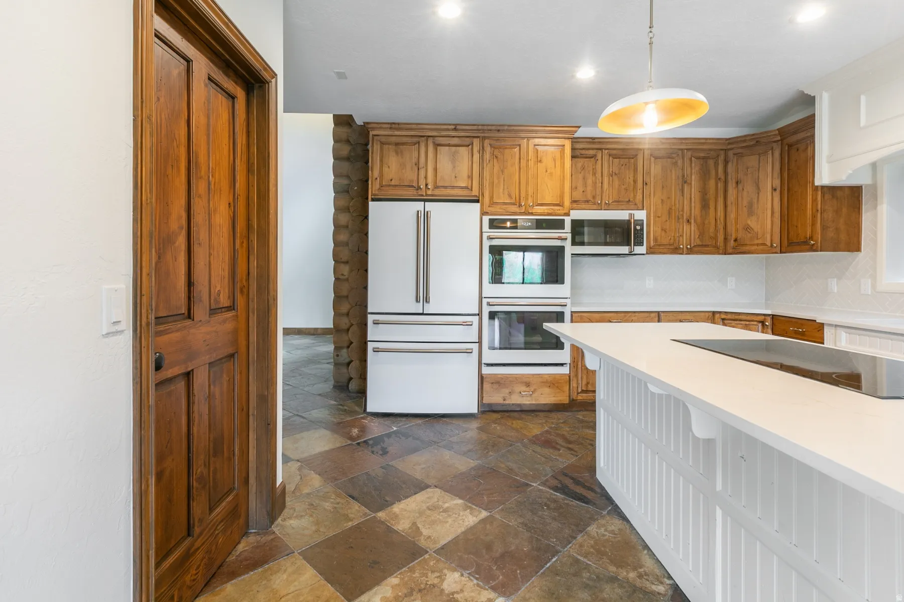 Kitchen featuring a large center island with white beadboard paneling, integrated cooktop, and light-toned countertop