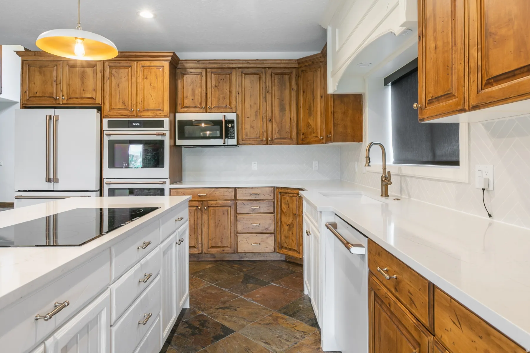 Kitchen featuring a large central island with an integrated cooktop, white countertops, and wood cabinetry