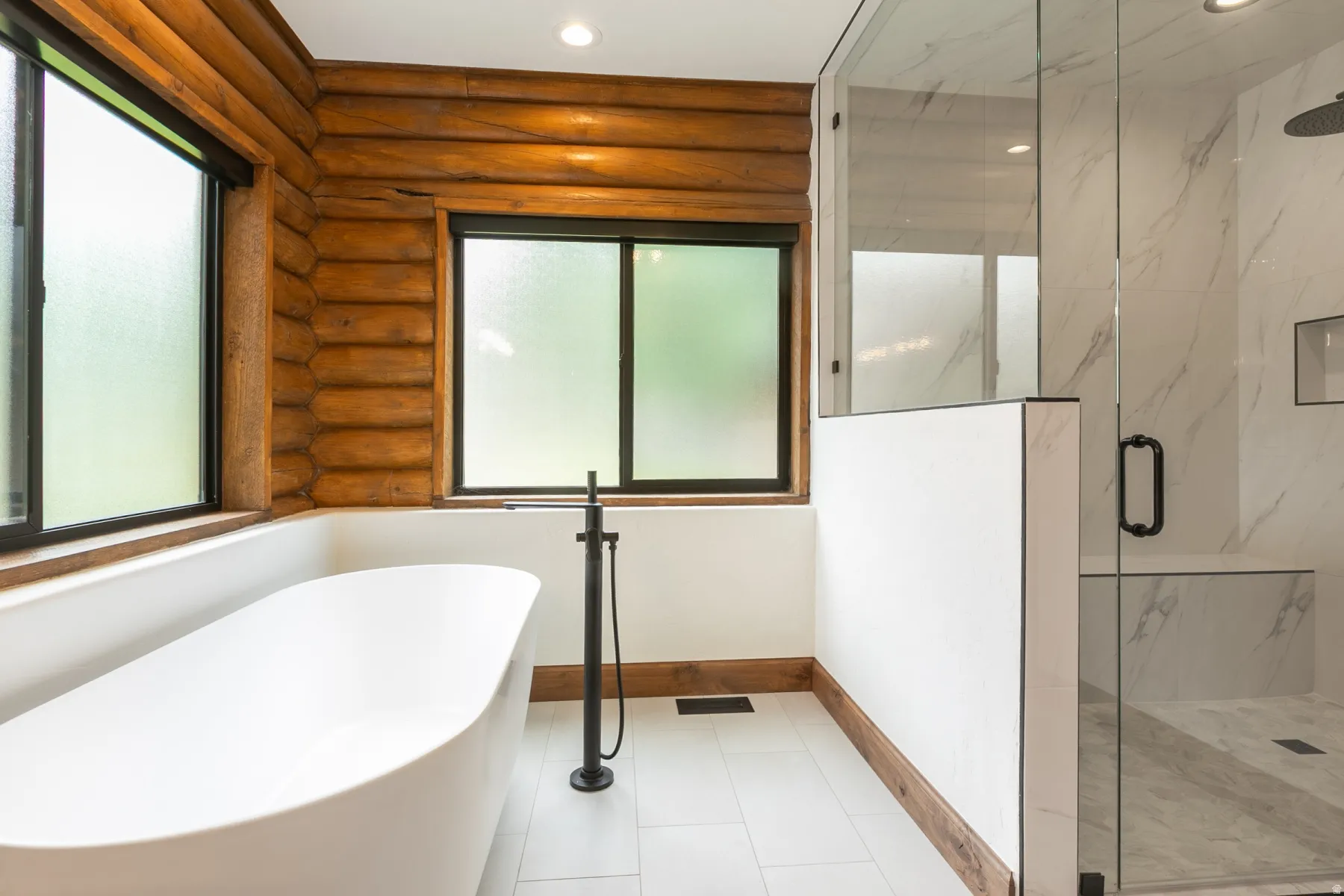 Freestanding soaking tub with a floor-mounted matte black faucet