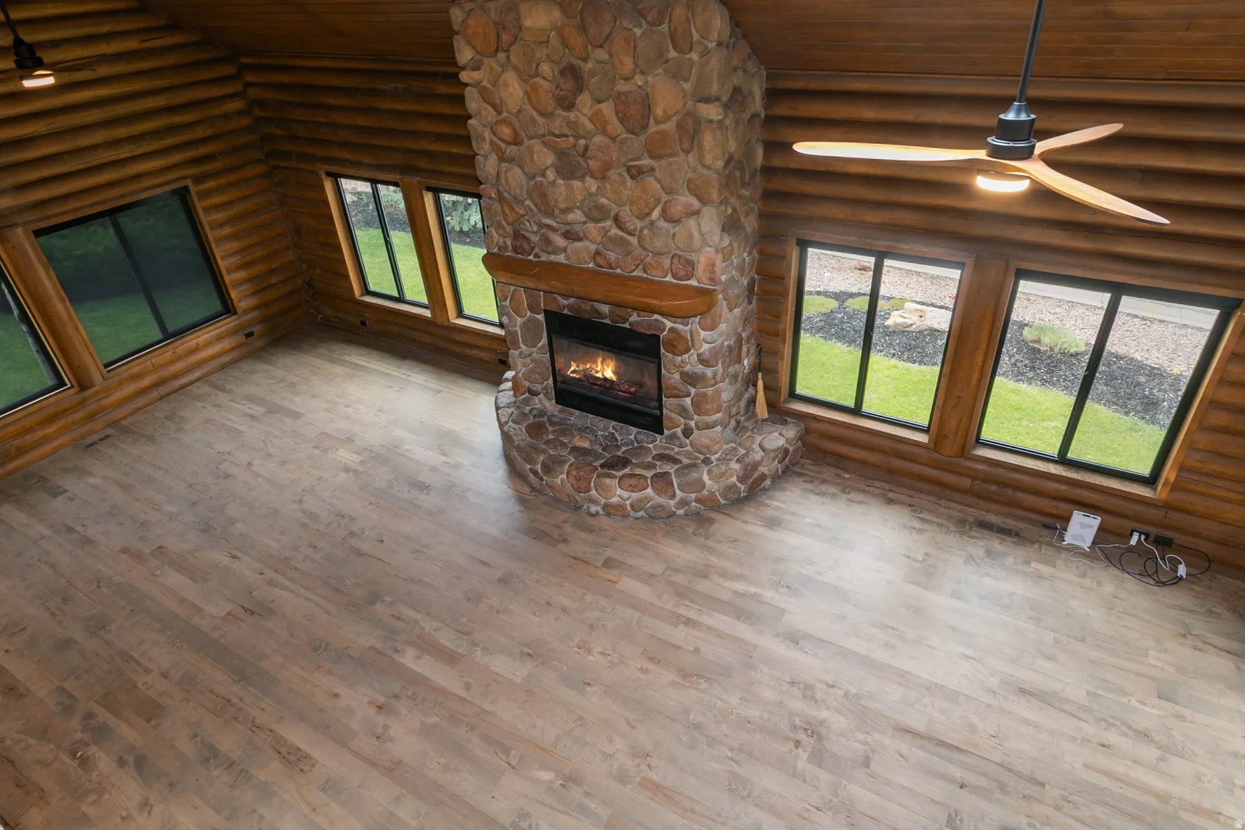 Spacious room featuring log-style wood walls and wood-finish flooring