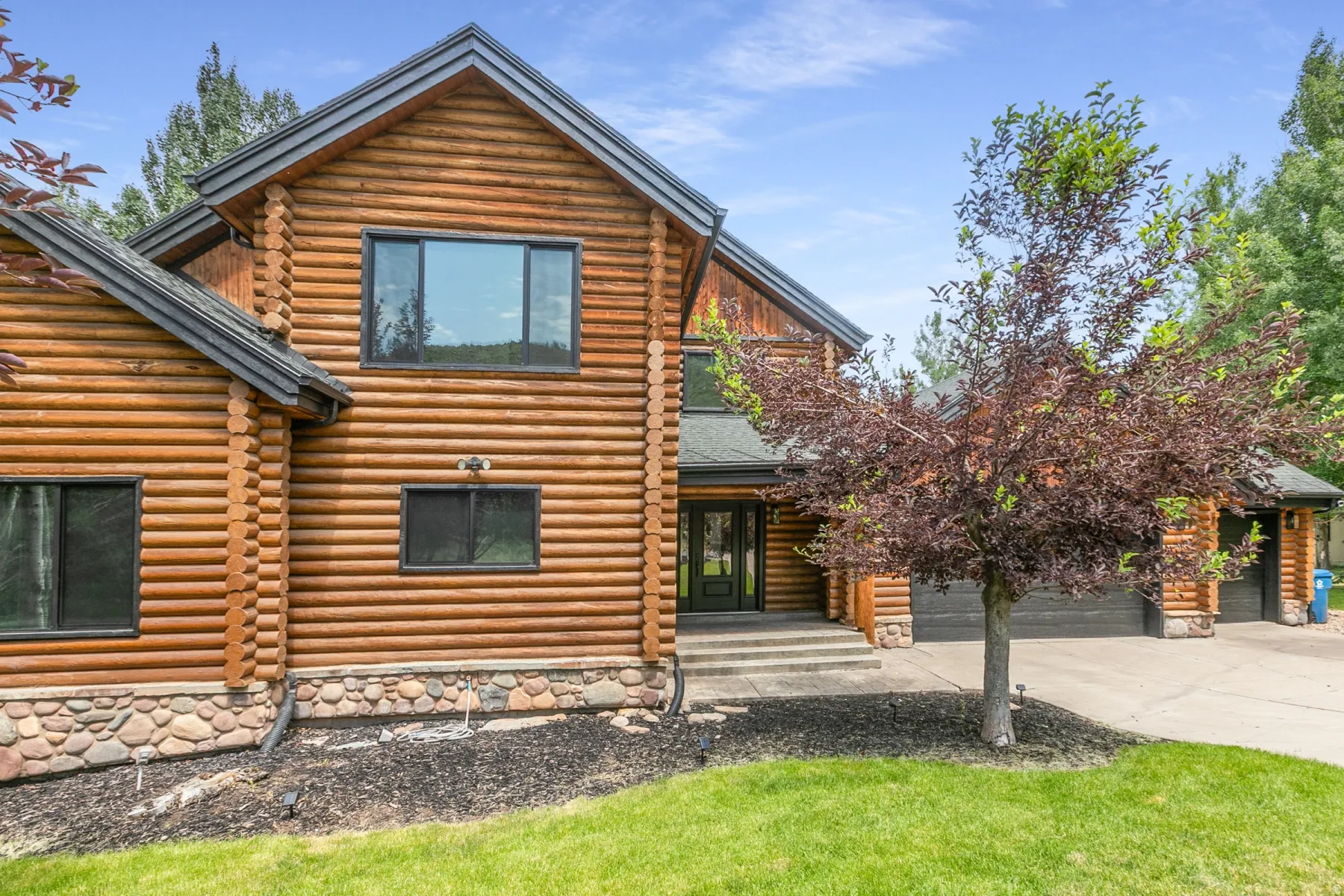 Log home exterior featuring a prominent gabled roofline and natural wood siding