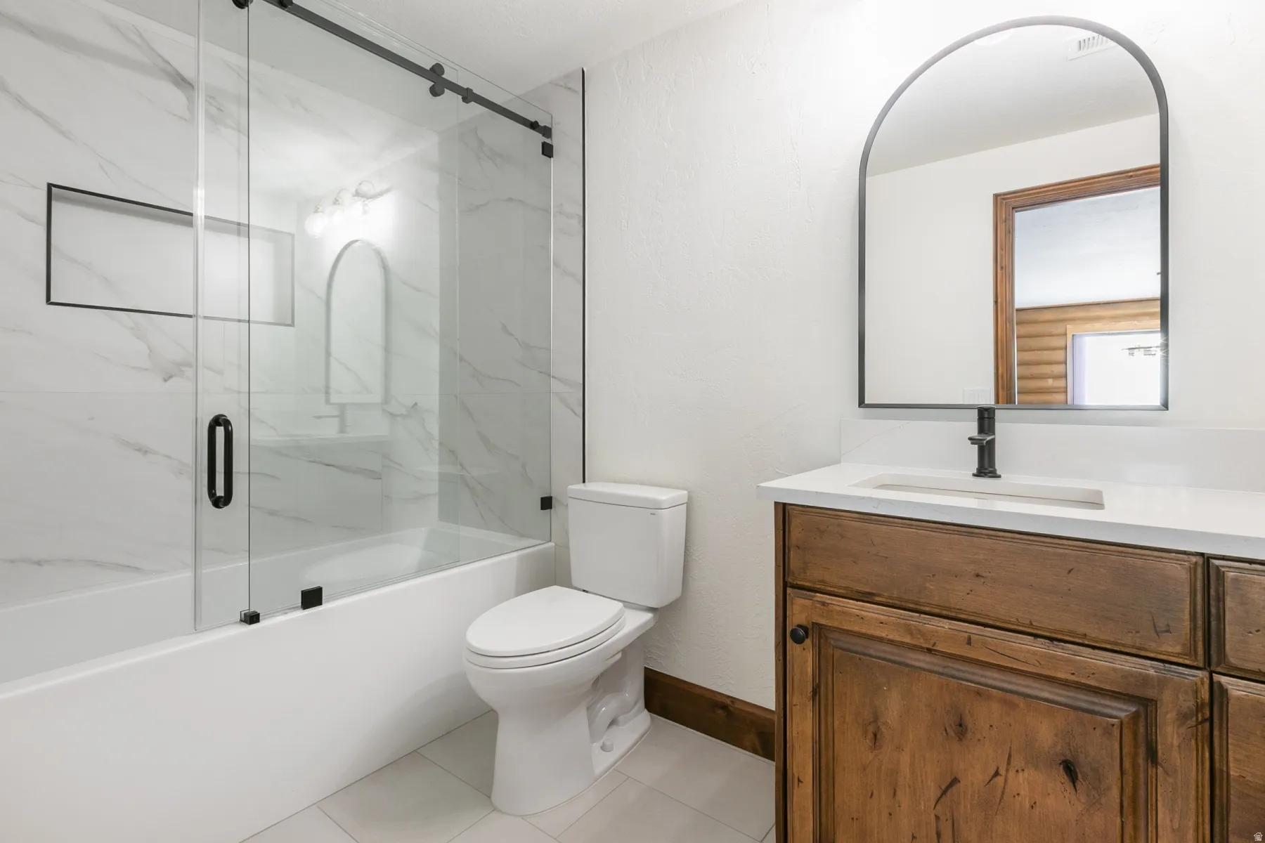 Bathroom featuring a tub/shower combination with a sliding glass door, white subway tile surround, and a built-in shower niche