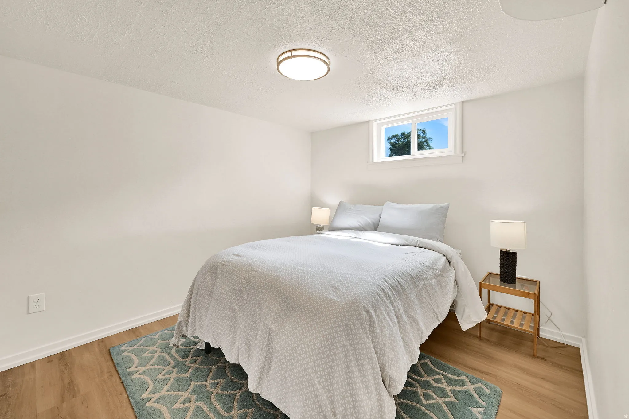 Bright room featuring light wood-finish flooring, white baseboards, and a window with white trim