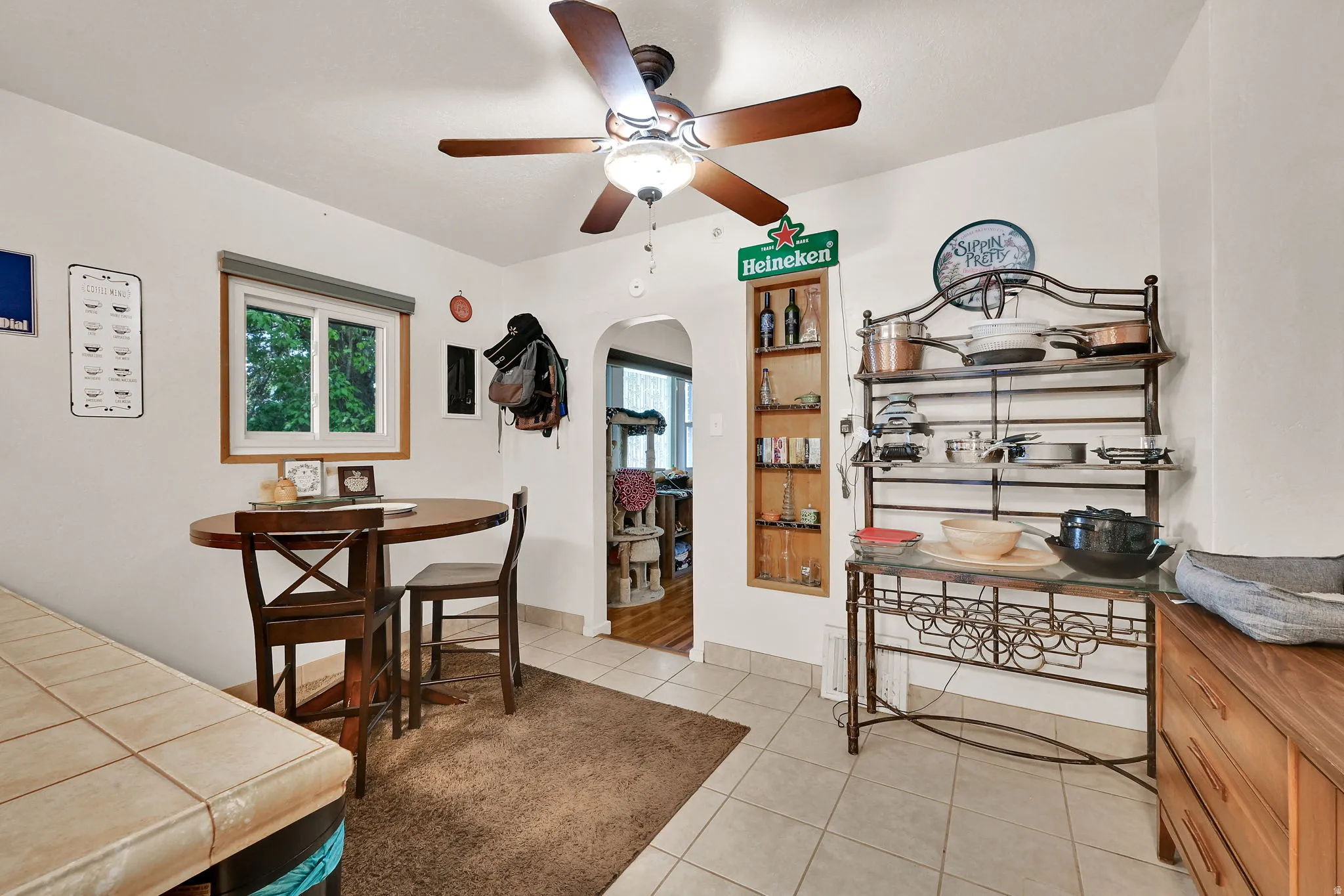 Tile flooring with an area rug, a ceiling fan with integrated lighting, and a built-in shelving unit