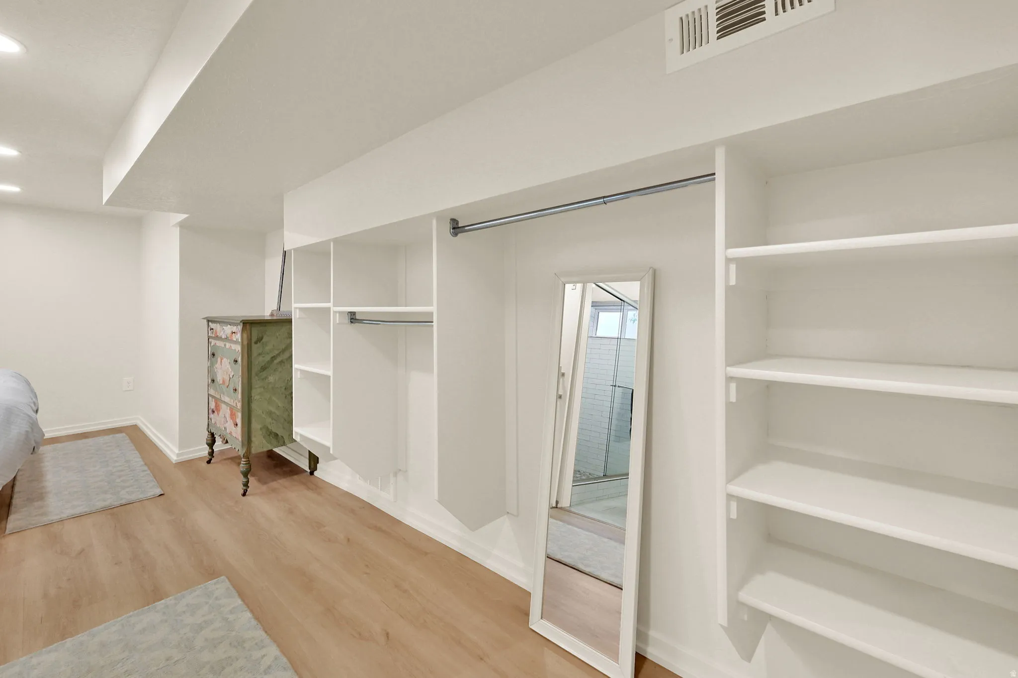 Built-in closet system featuring white shelving, hanging rods, and recessed lighting