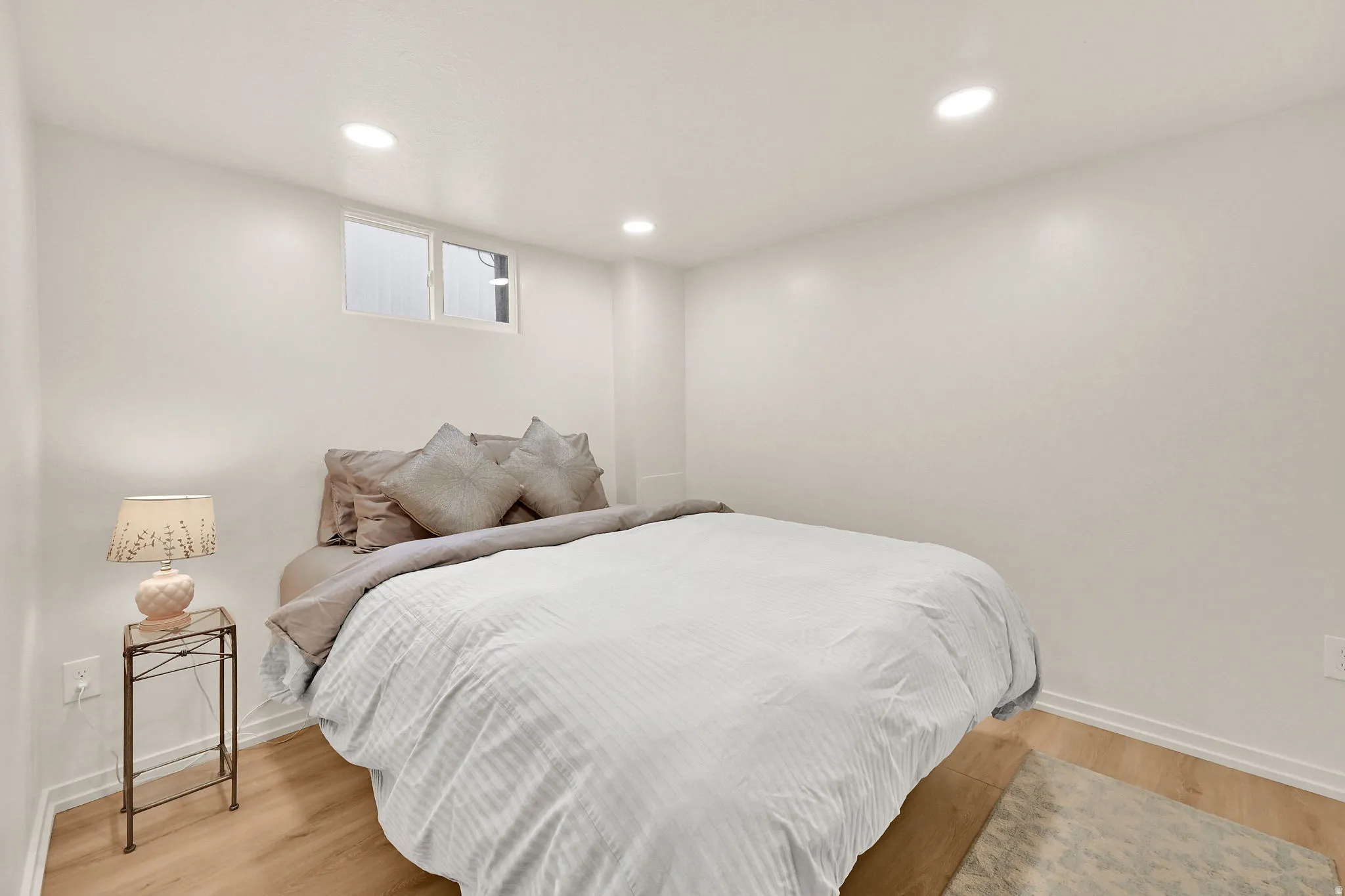 Recessed ceiling lighting, wood-finish flooring, and white baseboards