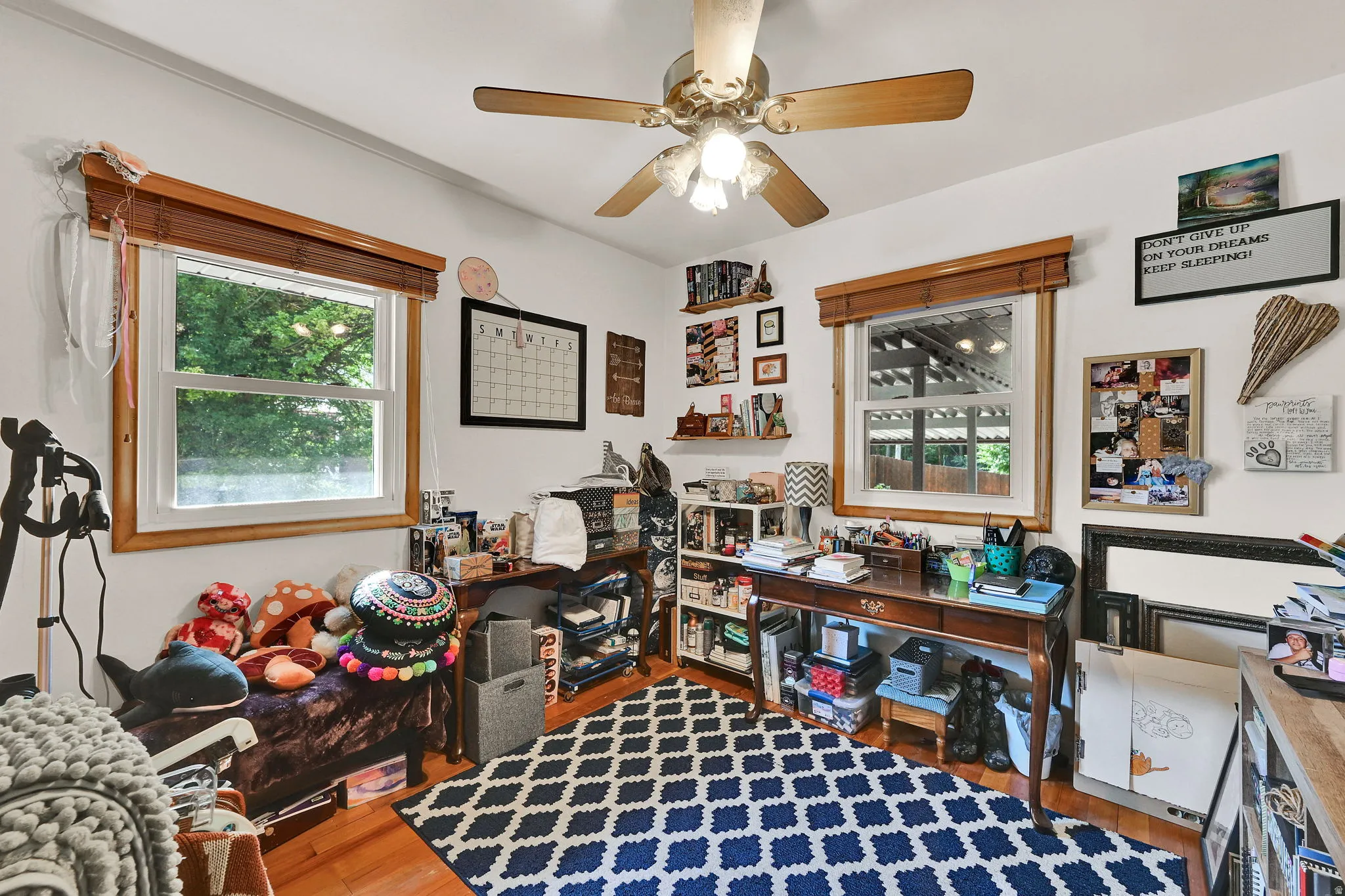 Room featuring wood-finish flooring, white walls, and a ceiling fan with light fixture