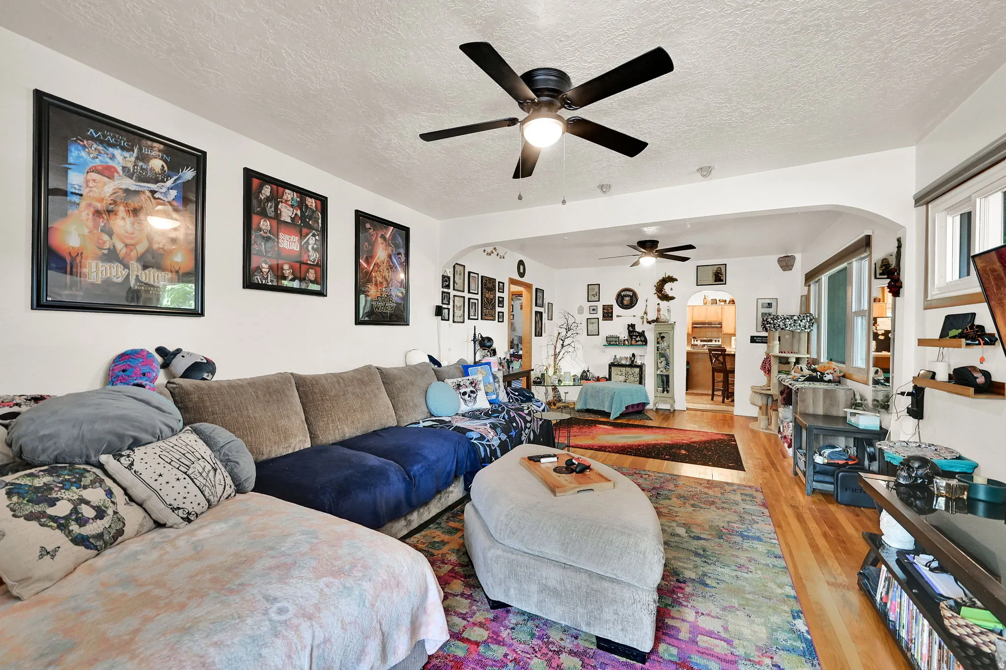 Spacious interior featuring a ceiling fan with integrated lighting, wood-finish flooring, and white walls