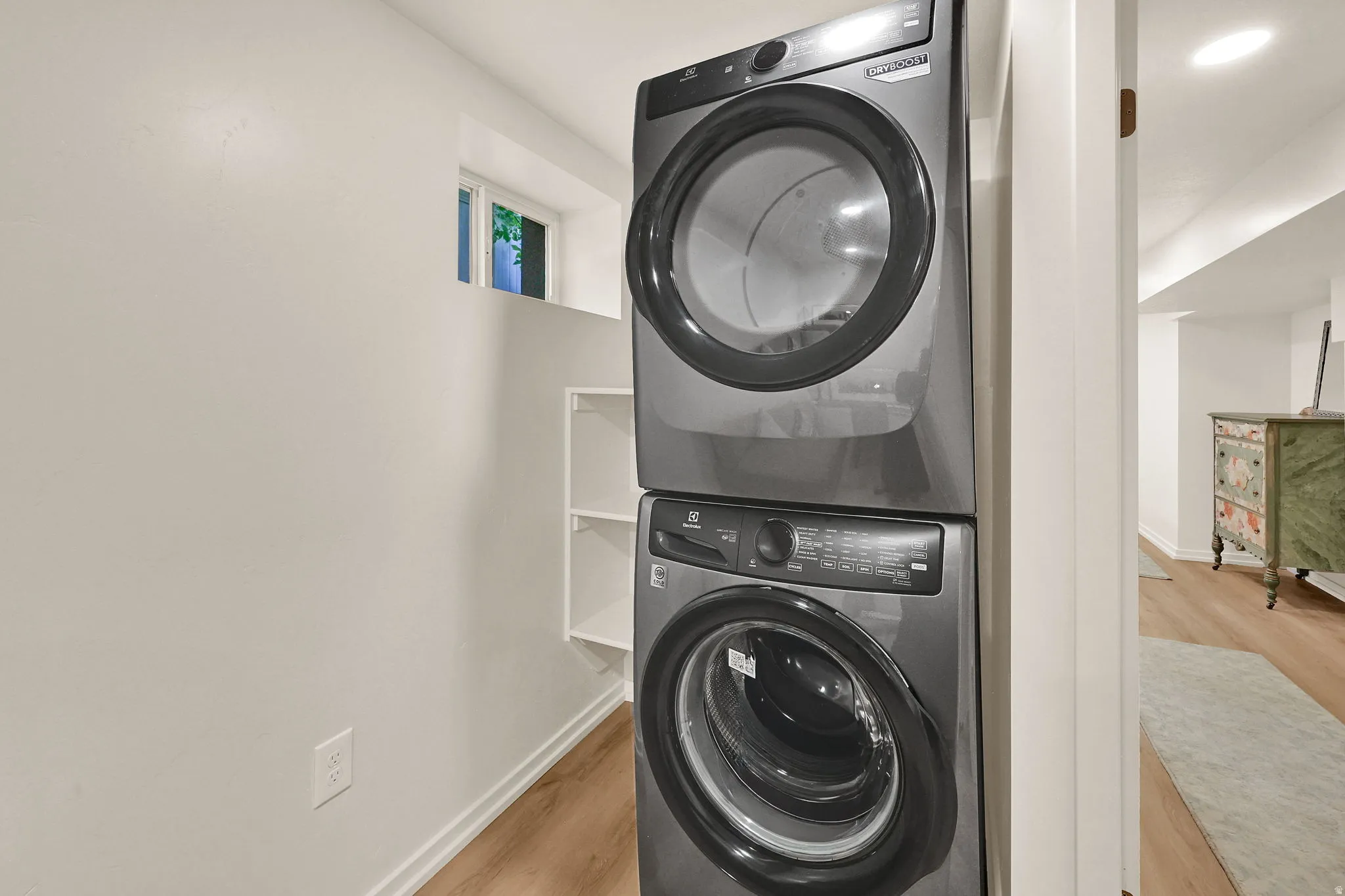 Dedicated laundry area featuring stacked appliances and built-in shelving