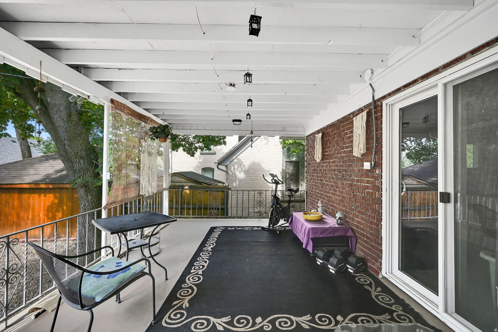 Covered outdoor patio featuring a brick wall and white painted overhead beams