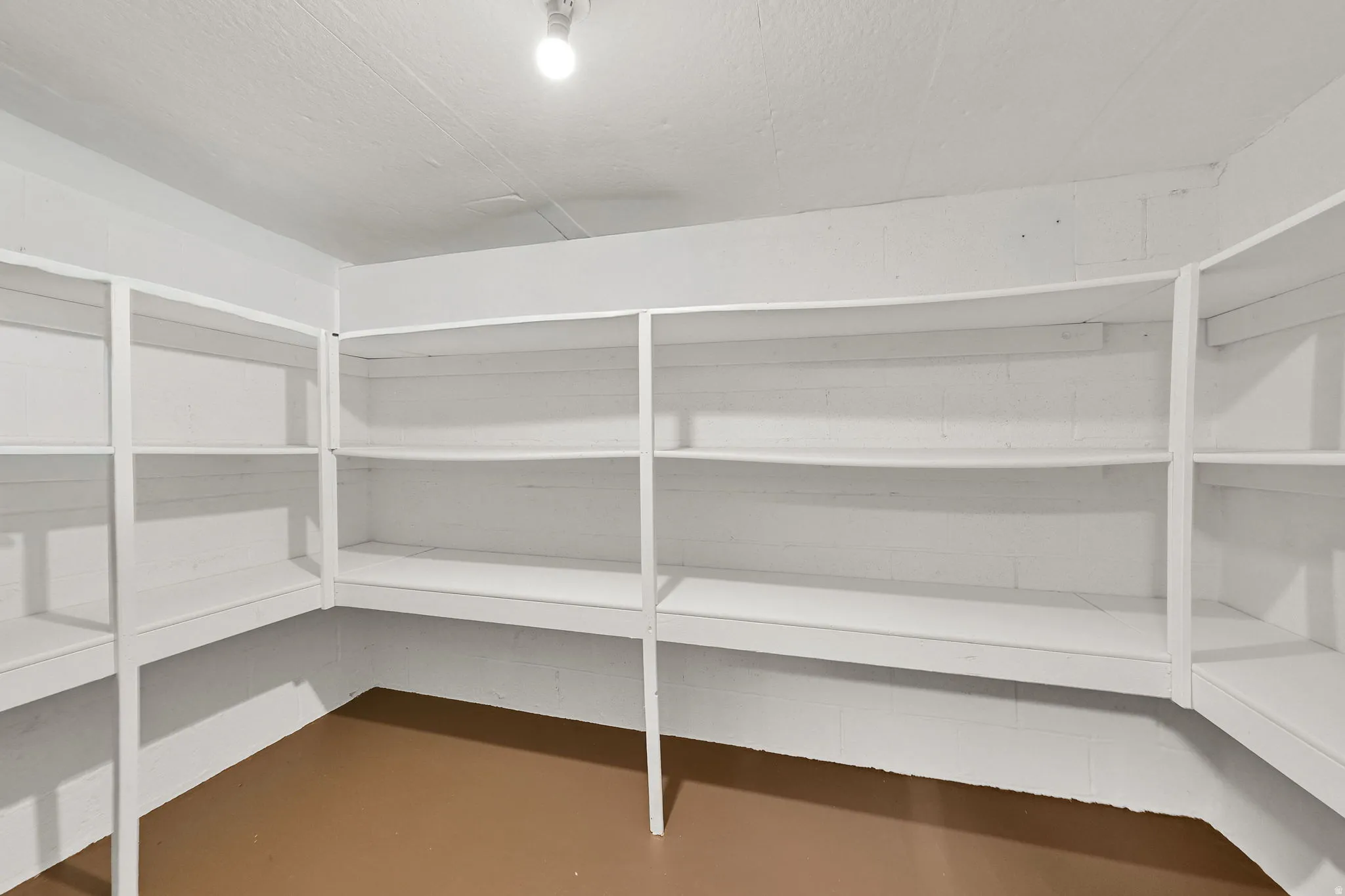 Utility room featuring extensive built-in shelving, painted white walls, painted white ceiling, and a light-toned floor