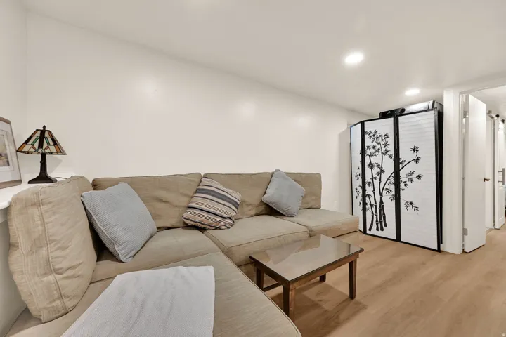 Recessed lighting illuminates this room, featuring wood-finish flooring and a neutral color palette