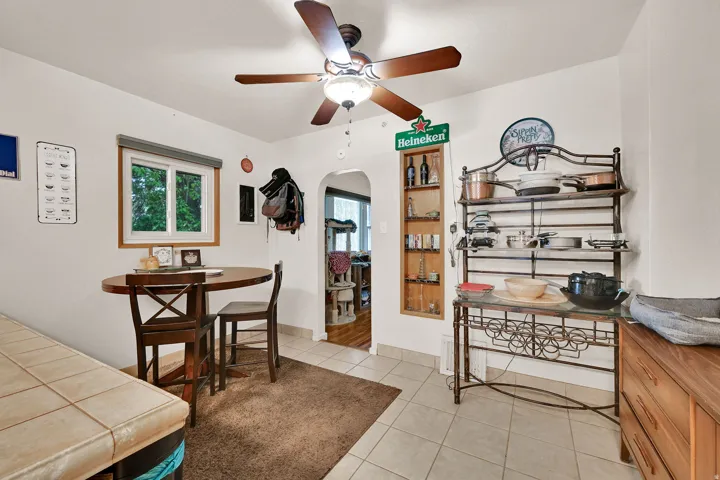 Tile flooring with an area rug, a ceiling fan with integrated lighting, and a built-in shelving unit