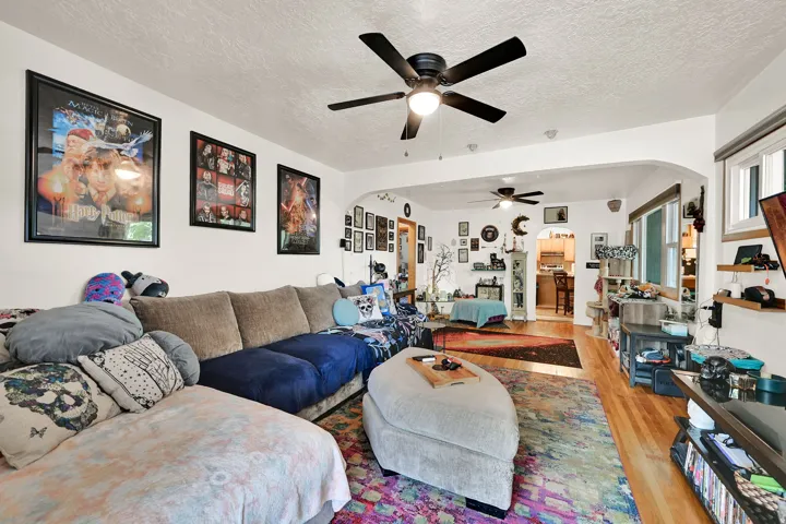 Spacious interior featuring a ceiling fan with integrated lighting, wood-finish flooring, and white walls