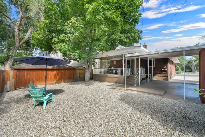 Gravel yard featuring mature trees and a wood privacy fence