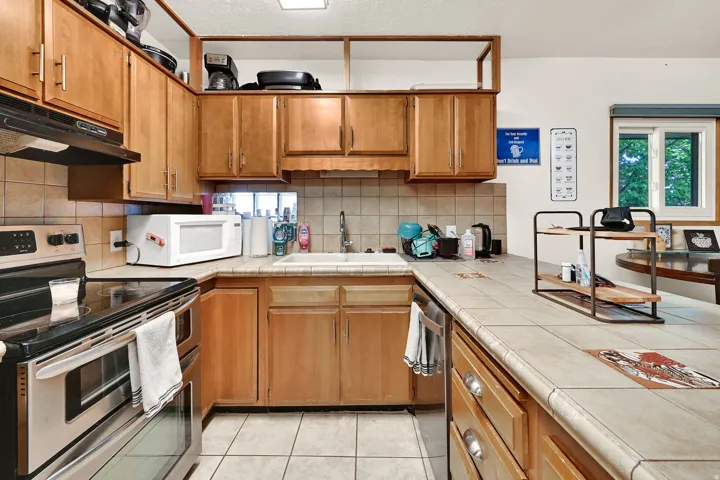 Kitchen featuring wood-finish cabinetry, tile countertops, and a tile backsplash