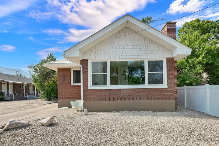 Brick exterior with white shingle siding and a prominent front window