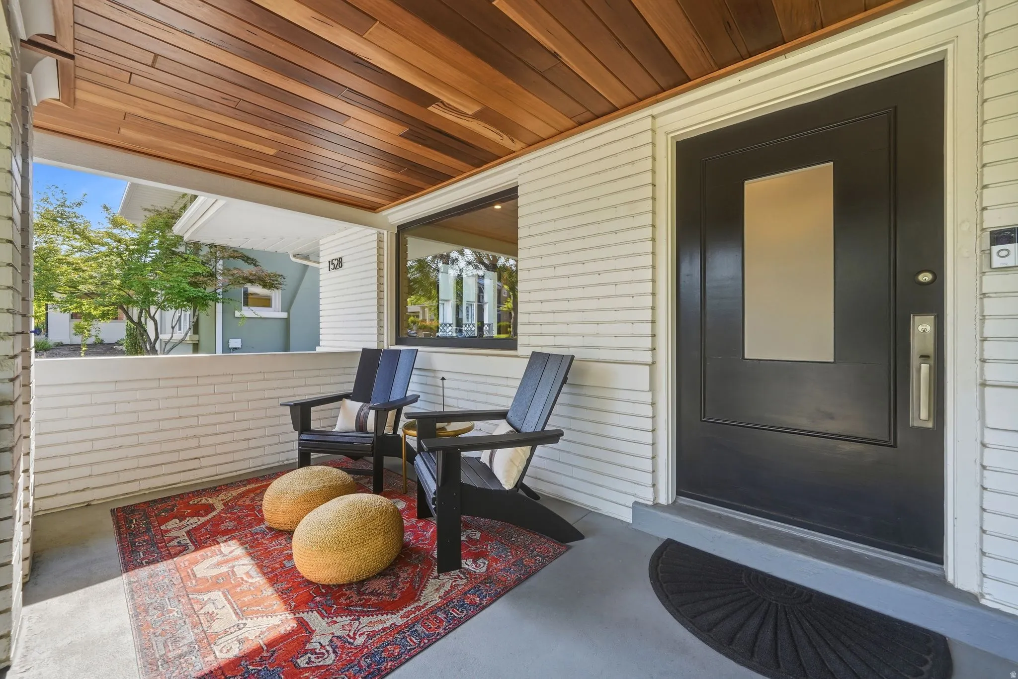 Covered front porch with brand-new Brazilian walnut ceiling, black metal railings, spacious seating area, & timeless Craftsman charm