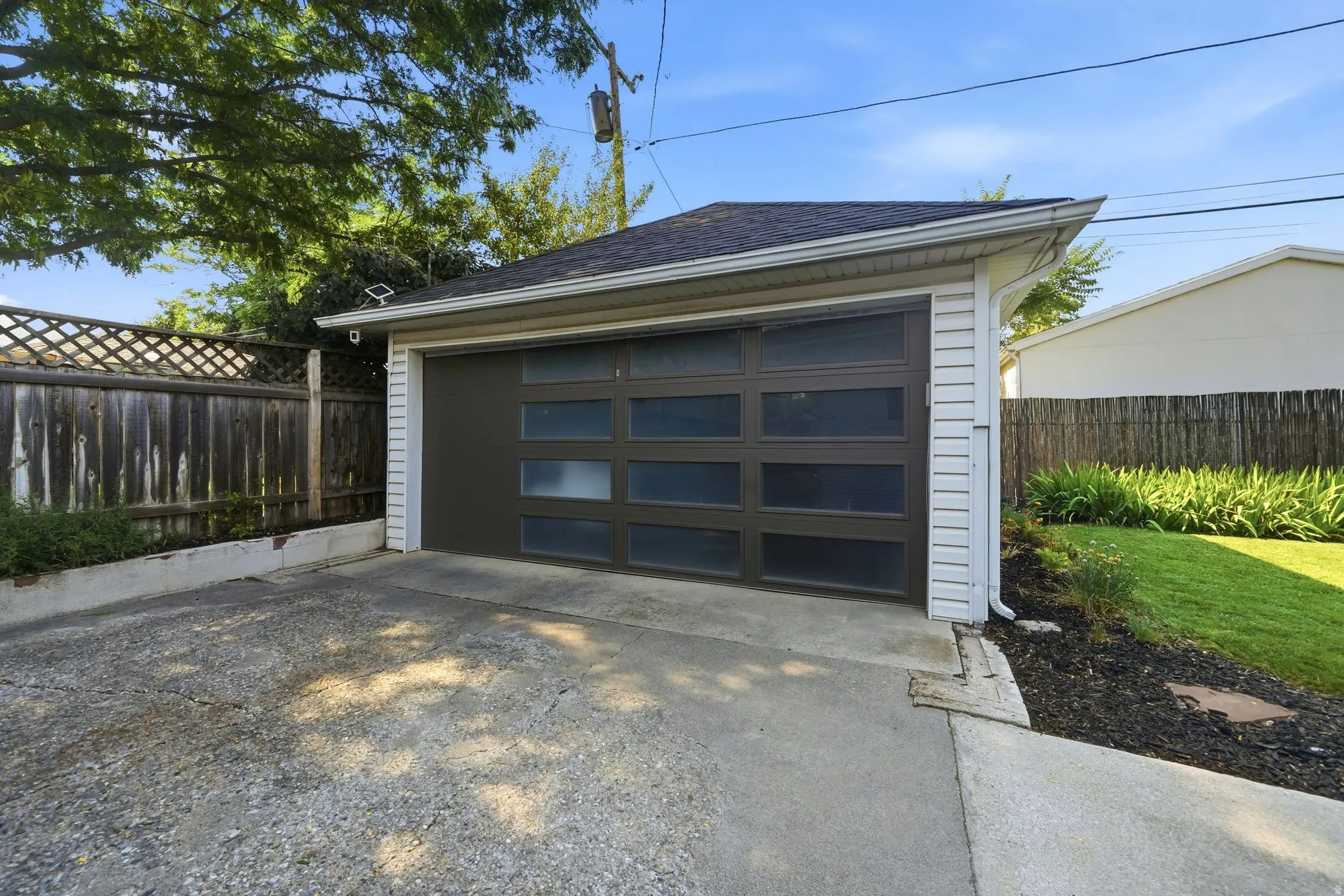 Detached garage horizontal frosted glass panels.  EV car charger on side of house near garage.