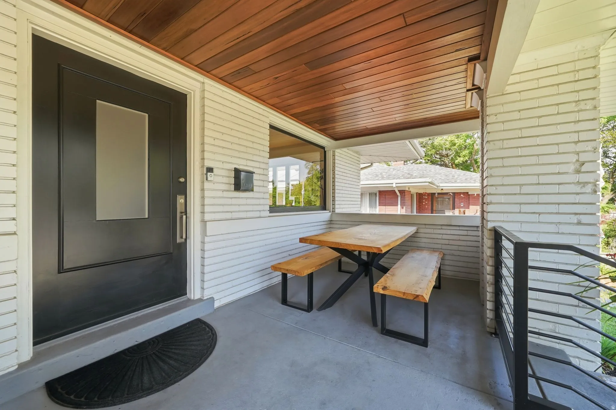 Covered front porch with brand-new Brazilian walnut ceiling, black metal railings, spacious seating area, & timeless Craftsman charm