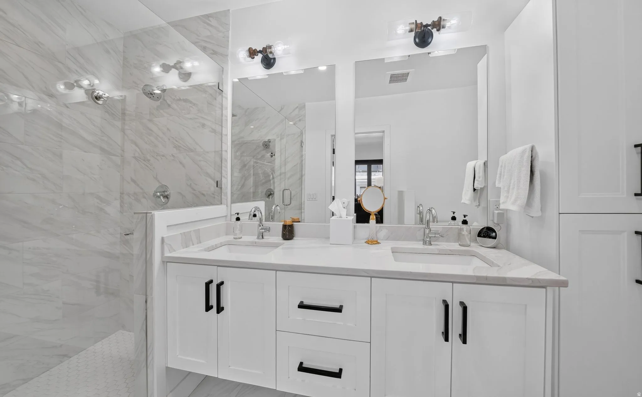 Primary bathroom retreat.  Dual vanity, quartz countertops, spa walk-in shower with euro glass enclosure, and custom linen cabinet.
