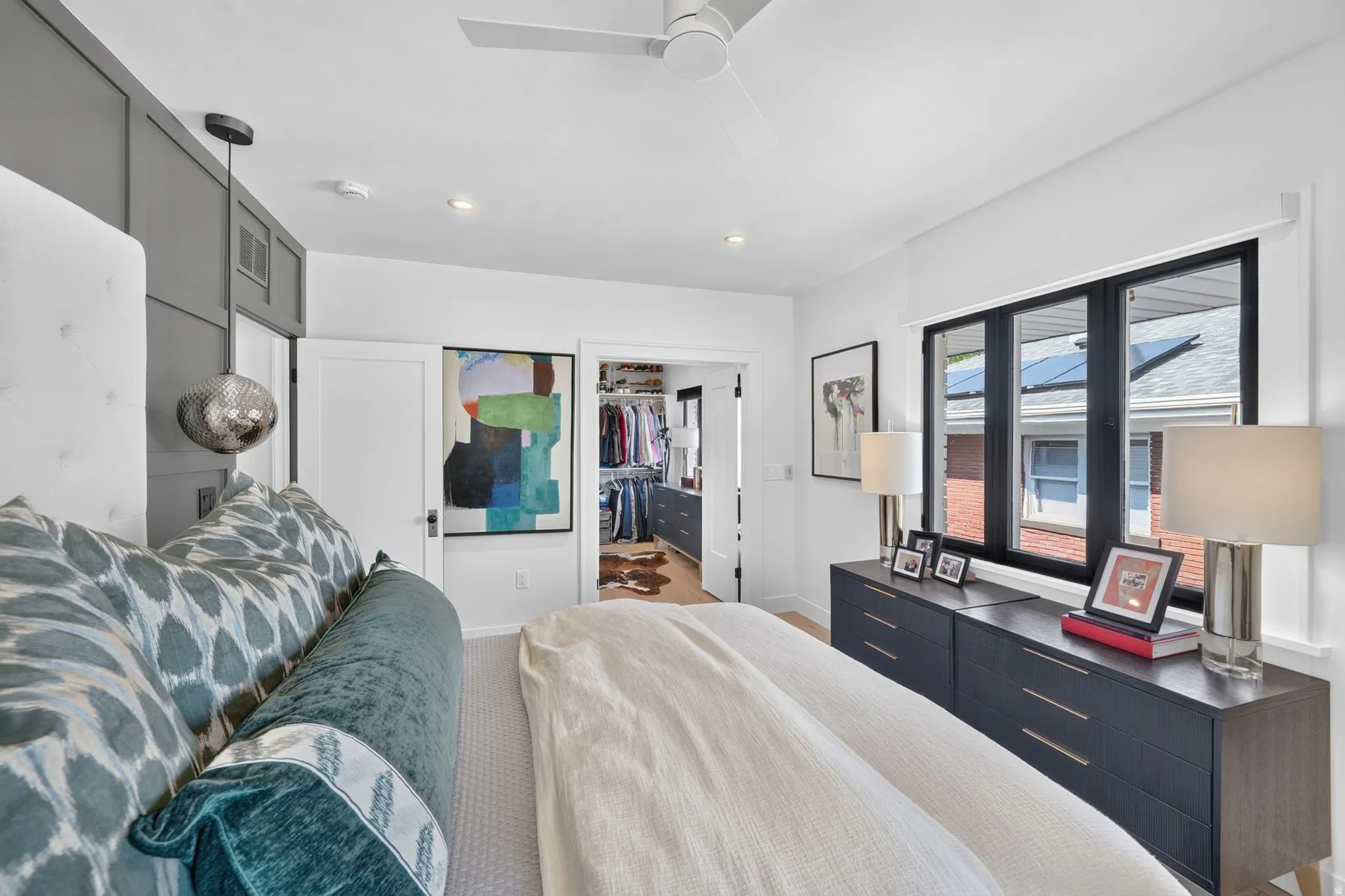Main floor primary retreat.  Black trim windows, custom motorized dual-direction shades, accent board & batten wall, custom side lamps, and large walk-in closet.