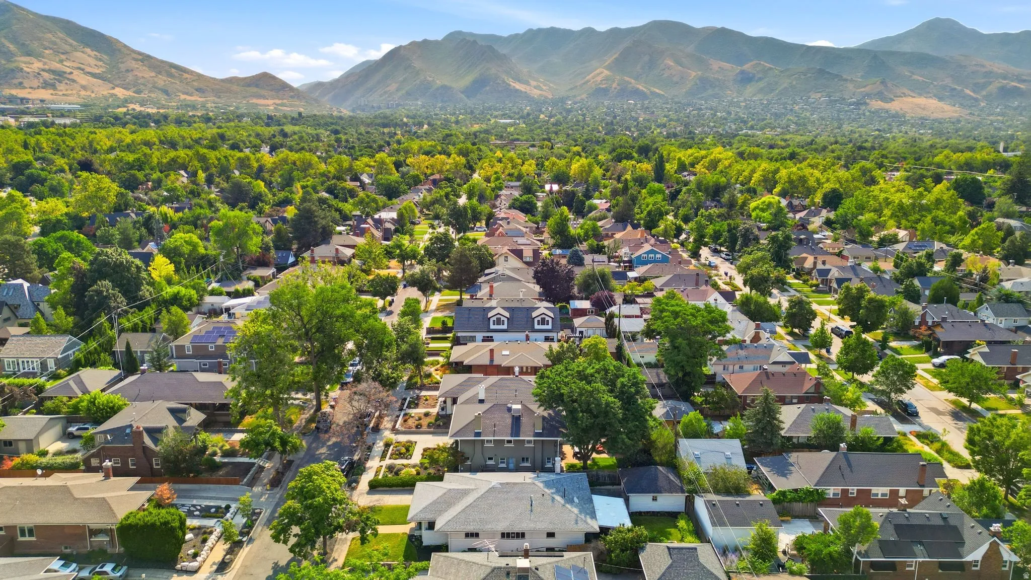 Expansive residential area featuring established homes, mature trees, and mountainous terrain in the background